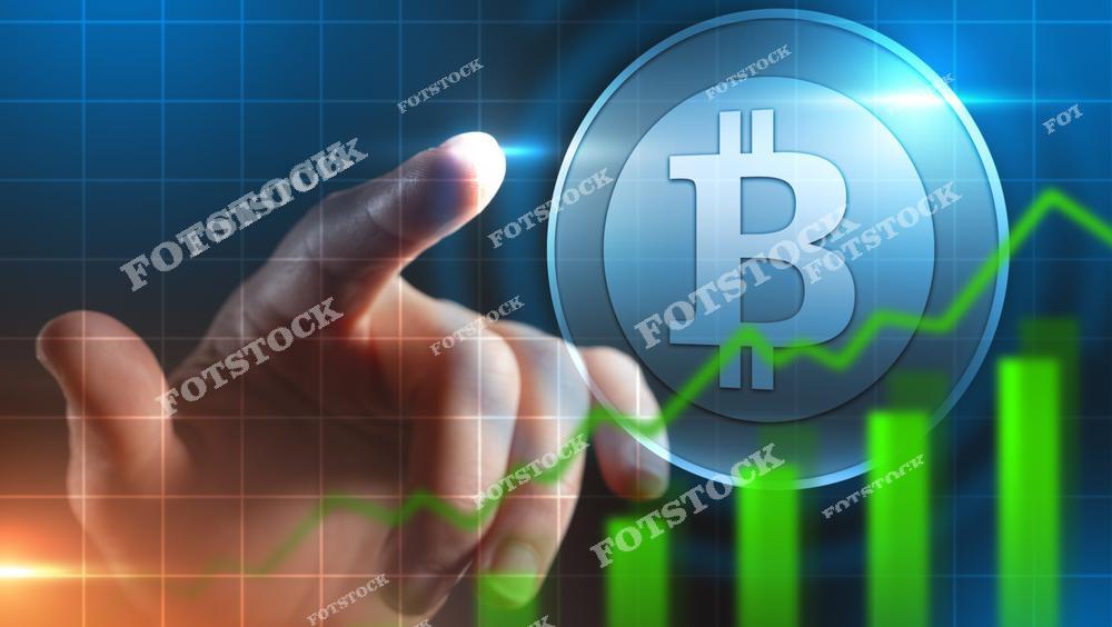 На изображении рука человека указывает на символ биткойна на фоне цифрового графика с растущими зелёными столбцами и линией. Сцена символизирует рост курса криптовалют, инвестиции в блокчейн, децентрализованные финансы и технологическое будущее цифровых активов.